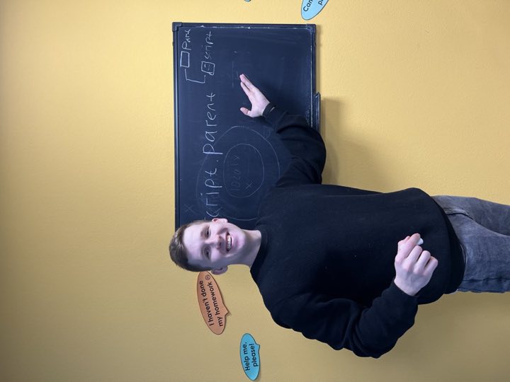 Преподаватель у доски объясняет тему и улыбается